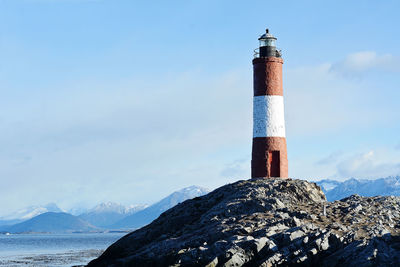 Lighthouse by sea against sky during winter