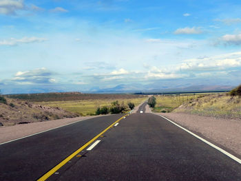 Road by landscape against blue sky
