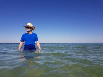 Man standing in sea against sky