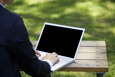 Midsection of man using mobile phone in park