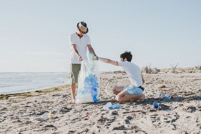 Men collecting garbage on beach