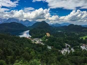 Scenic view of hohenschwangau castle by alpsee amidst trees against sky