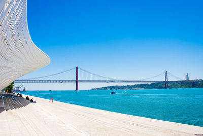 Low angle view of suspension bridge against clear blue sky