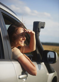 Smiling woman shielding eyes in car