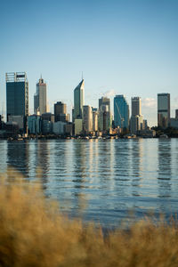 Buildings by river against sky in city