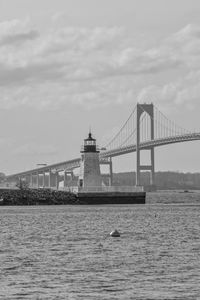 View of suspension bridge over water against cloudy sky