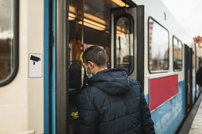 Mid adult man boarding tram during pandemic