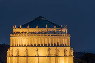 Illuminated building against blue sky at night