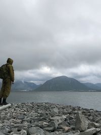Full length of man standing on rocks at beach against sky
