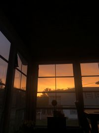 Silhouette buildings seen through window during sunset