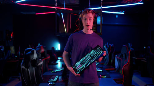 Portrait of young man standing in internet cafe