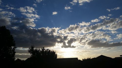 Silhouette of trees against cloudy sky