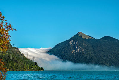 Scenic view of sea and mountains against clear blue sky