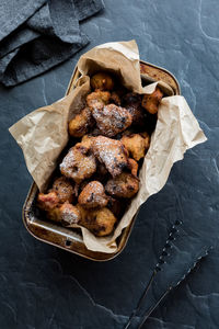A baking tin filled with fruit fritters sprinkled with icing sugar.