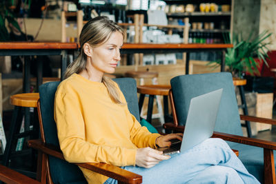 A woman sitting in a cafe works on a laptop.