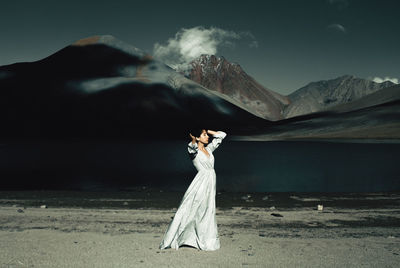 Woman standing on mountain against sky