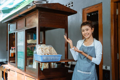 Portrait of smiling young woman standing against building