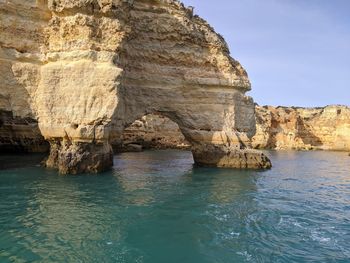 Rock formation in sea against sky