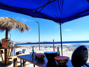 Chairs and tables on beach against sky