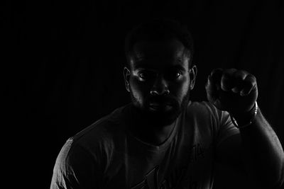 Portrait of mid adult man looking away while standing against black background