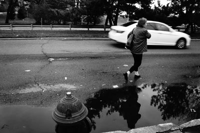 Full length of man walking by puddle on road
