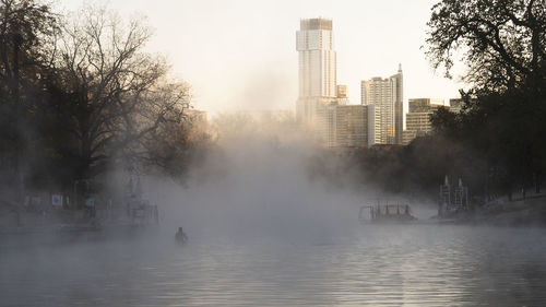 Scenic view of misty and foggy natural pool near downtown in city against morning sky