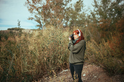 Full length of woman photographing on field