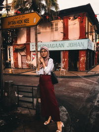 Portrait of smiling girl standing on sign in city