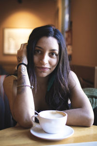 Portrait of woman with coffee cup on table in cafe