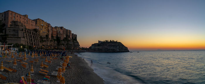 Panoramic view of sea and buildings against sky at sunset