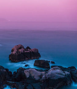 Rocks on sea shore against sky during sunset