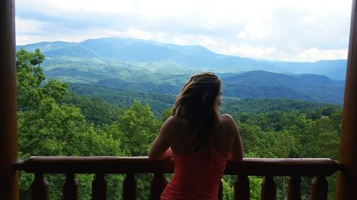 Rear view of woman in balcony looking at mountains