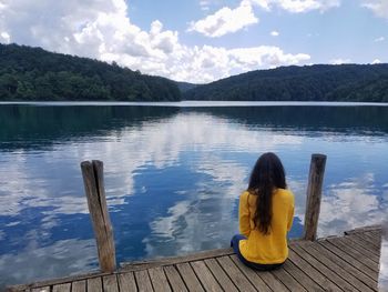 Rear view of woman looking at lake against sky