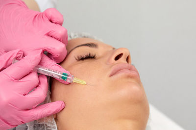 Close-up of doctor injecting syringe against white background