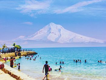 People on beach by mountain against sky