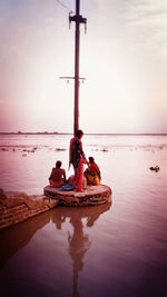 People on diving platform river against sky