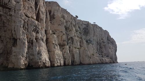 Scenic view of sea by mountain against sky