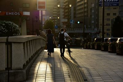 Rear view of people walking on street in city