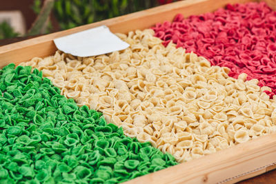 Fresh green, white and red orecchiette or orecchietta pasta drying under the sun on a wooden board