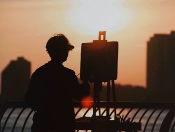 Rear view of silhouette man against sky during sunset