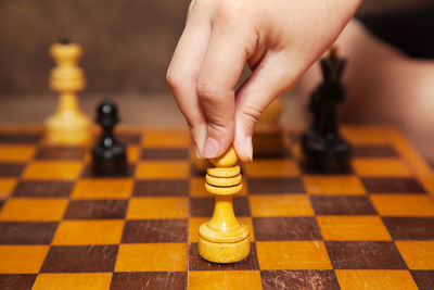 Close-up of cropped person playing chess at home
