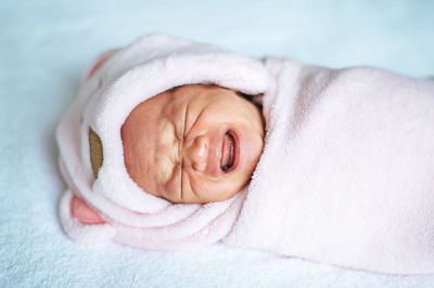 Close-up of newborn crying on bed