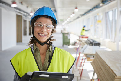 Portrait of smiling female foreman with digital tablet at construction site