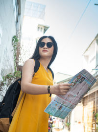 Portrait of young woman wearing sunglasses standing outdoors