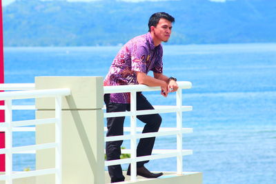 Portrait of a man on railing by water