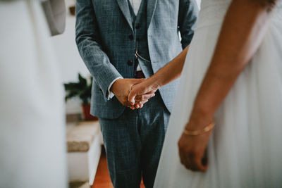 Midsection of couple holding hands during wedding ceremony