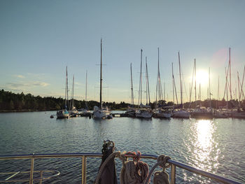 Sailboats moored at harbor during sunset