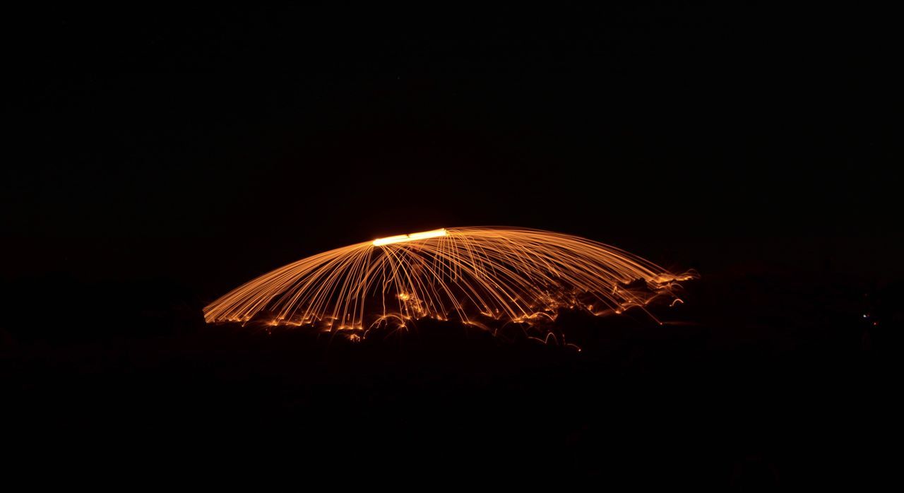 night, motion, illuminated, copy space, long exposure, dark, glowing, blurred motion, sky, burning, arts culture and entertainment, no people, nature, fire, outdoors, orange color, flame, fire - natural phenomenon, light - natural phenomenon, heat - temperature, wire wool, firework, sparks, black background