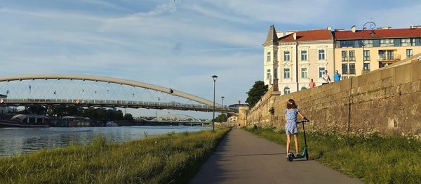 City landscape from the embankment of the great river vistula and a girl on a scooter.