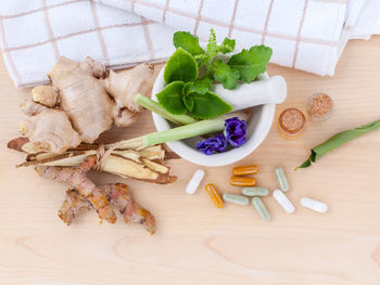 High angle view of herbs in spices with capsules on table